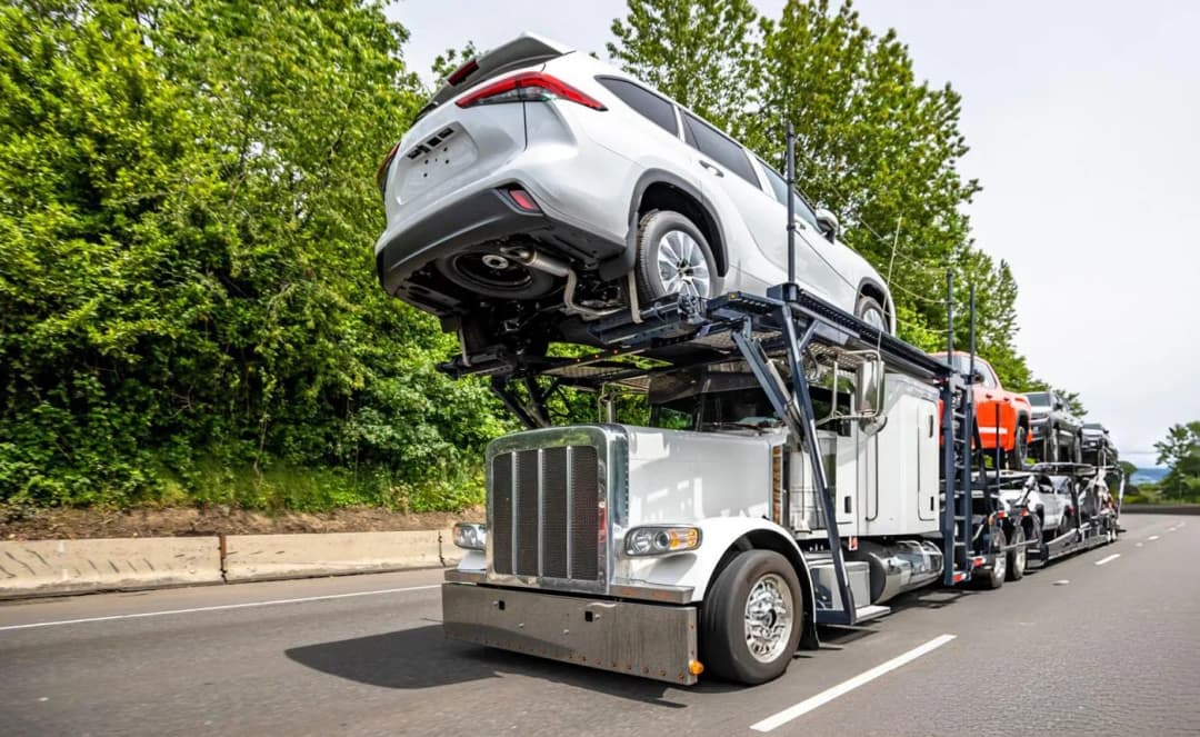 Open car transport trailer carrying multiple vehicles